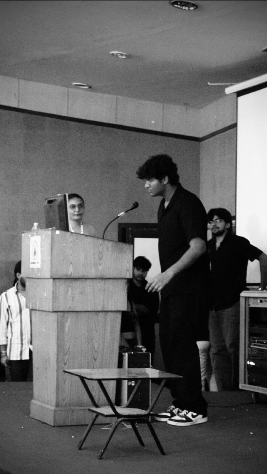 Siddharth Kumar speaking at a podium during a campus event.